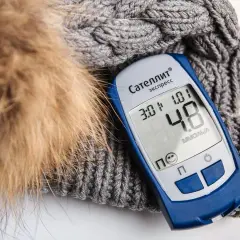Glukometr na tle zimowej czapki. Czy wódka zbija cukier? Wynik 4.8 mmol/l.