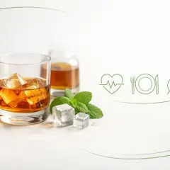 Szklanka whiskey z lodem, miętą i kłosami zbóż. Obok ikony serca, talerza i liścia. Czy whiskey jest zdrowe?