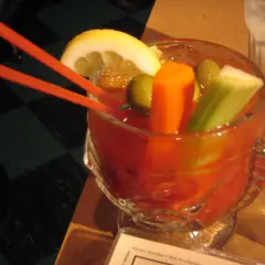 Krwawa Mery przepis: czerwony drink z cytryną, oliwkami, selerem i marchewką, podany z pomarańczowymi słomkami.
