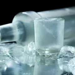 Chłodna wódka w kieliszku i butelce, otoczona lodem. Czy wódka może się przeterminować? Nie, jeśli jest przechowywana prawidłowo.