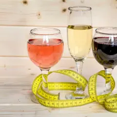 Trzy kieliszki z winem i miarka krawiecka. Zastanawiasz się, ile kcal ma setka wódki?