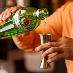 Barman nalewa gin do kieliszka, przygotowując idealny martini.