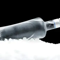 Szklana butelka wódki leży w lodzie, pokazując, dlaczego wódka zamarza w zamrażarce.
