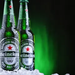 Trzy butelki Heineken, holenderskiej marki piwa, w lodzie.