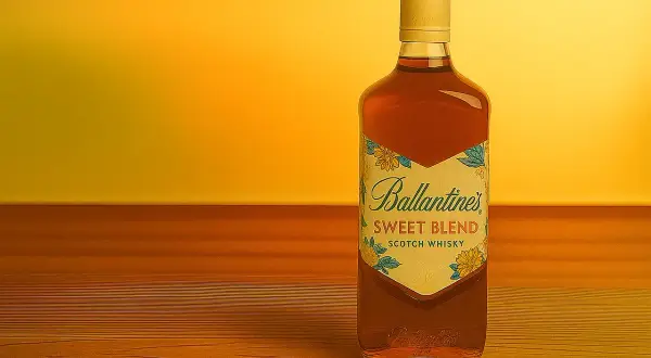 Butelka Ballantine's Sweet Blend Scotch Whisky na drewnianym blacie. Dowiedz się, jak pić balantajsa, by docenić jego smak.