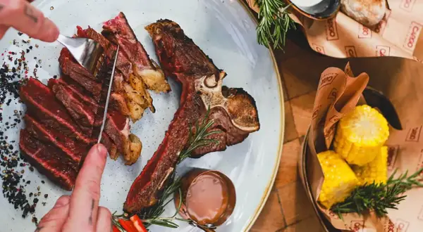 Idealne jakie wino do wołowiny? Soczysty stek T-bone z pieczonymi ziemniakami i kukurydzą.