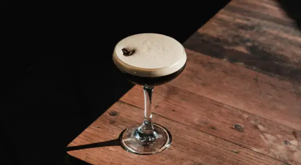 Elegancki kieliszek z pianką, ozdobiony ziarnem kawy, idealny do delektowania się drinkiem espresso martini.