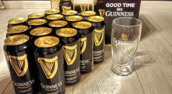 Dużo puszek piwa Guinness i szklanka, gotowe na dobrą zabawę.