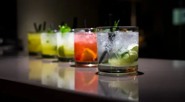 Rząd kolorowych, prostych drinków z wódką, z lodem i miętą, gotowych do podania.