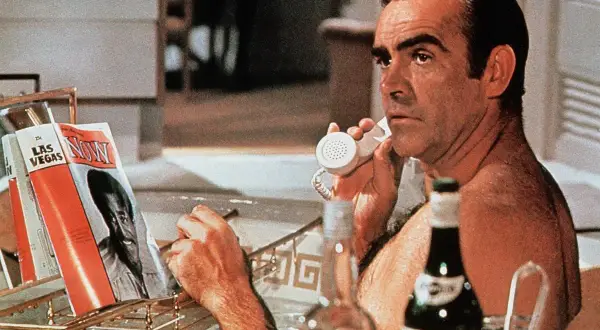 Sean Connery jako James Bond, w wannie, rozmawia przez telefon, obok butelka Martini wstrząśnięte nie mieszane i magazyn "Now".