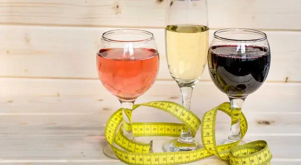 Trzy kieliszki z winem i miarka krawiecka. Zastanawiasz się, ile kcal ma setka wódki?