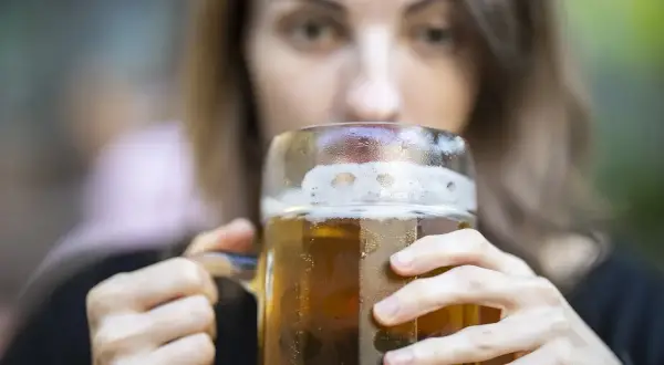 Kobieta pije piwo z dużego kufla. Zastanawiasz się, ile kalorii ma piwo smakowe?