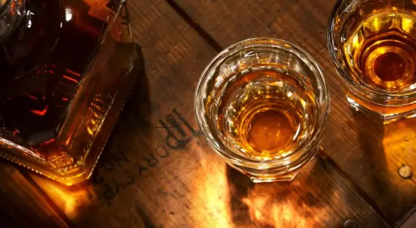 Butelka i dwa kieliszki z bursztynowym płynem na drewnianym blacie. Czy koniak to whisky?