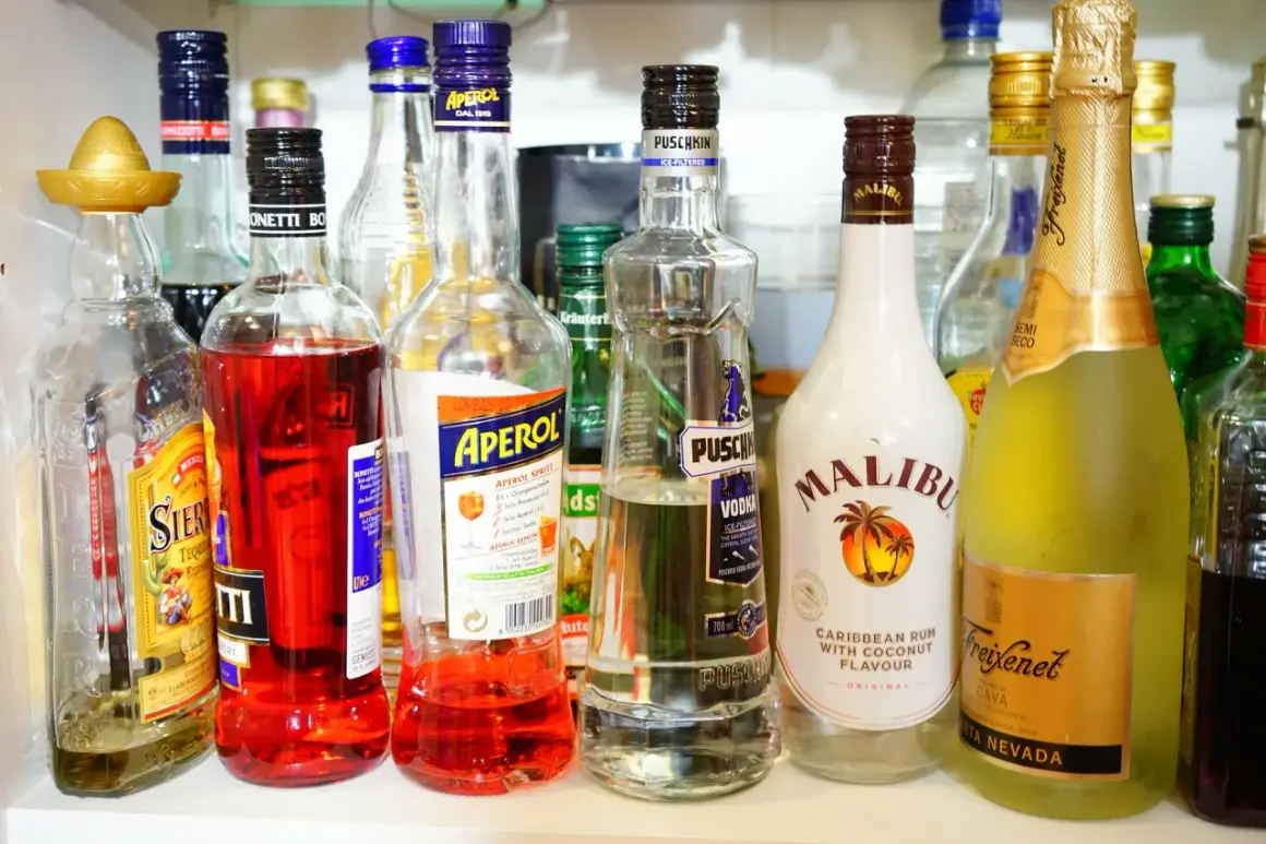 Na półce stoją butelki z różnymi alkoholami. Wśród nich wódka Puschkin, która ma 40% alkoholu, Aperol, Malibu i Freixenet.