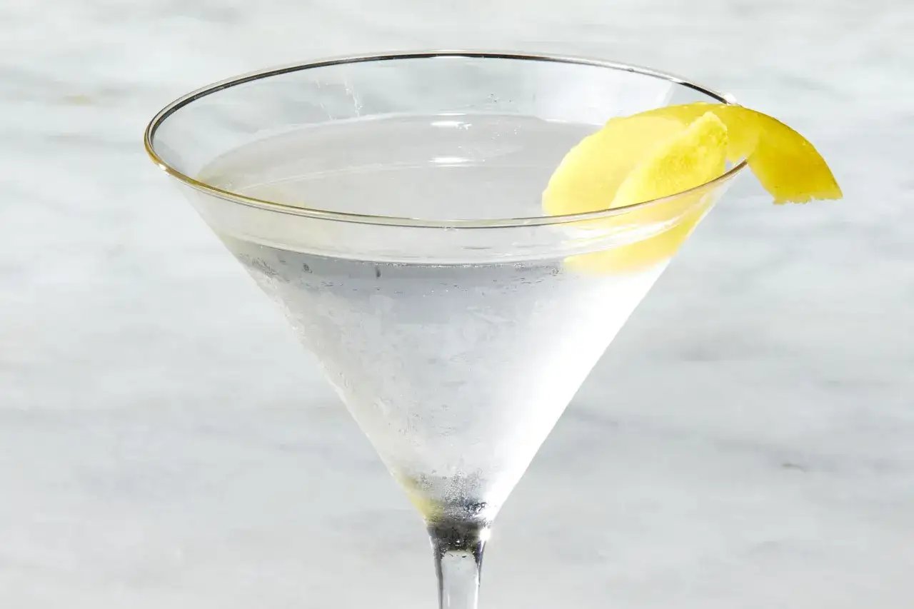 Schłodzone martini w kieliszku, ozdobione skórką cytryny. Idealne, by dowiedzieć się, jak pić martini.