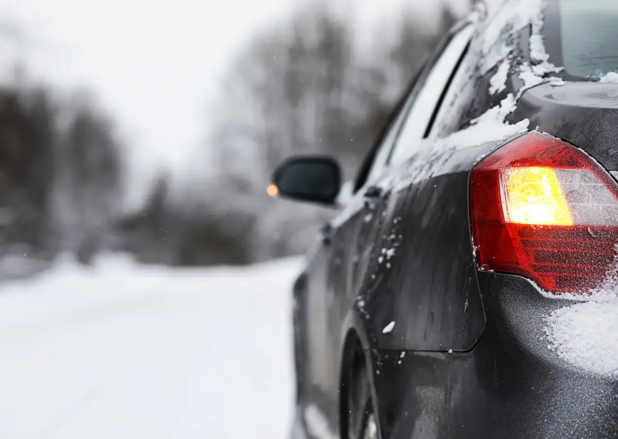 Zimowa podróż. Czy piwo zamarznie w bagażniku? Auto na zaśnieżonej drodze, w tle drzewa.