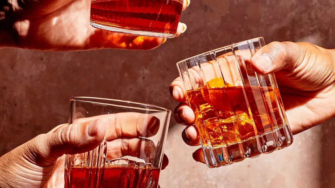 Trzy dłonie unoszą szklanki z bursztynowym trunkiem. Zastanawiasz się, ile procent ma whisky?